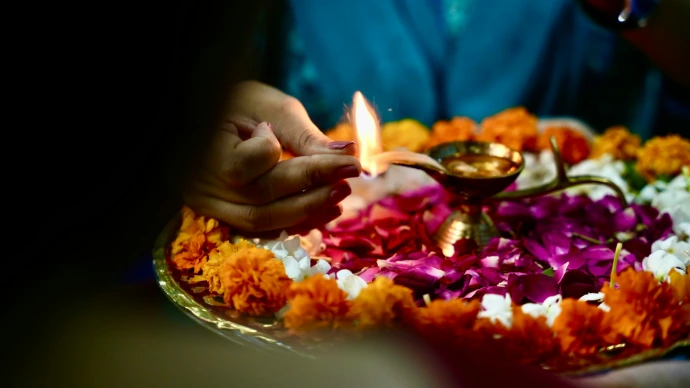 A person lighting a candle on a plate of flowers